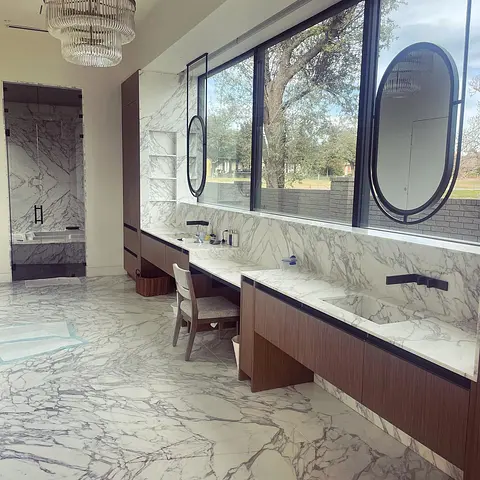 Twin black-framed oval mirrors above a marble double vanity